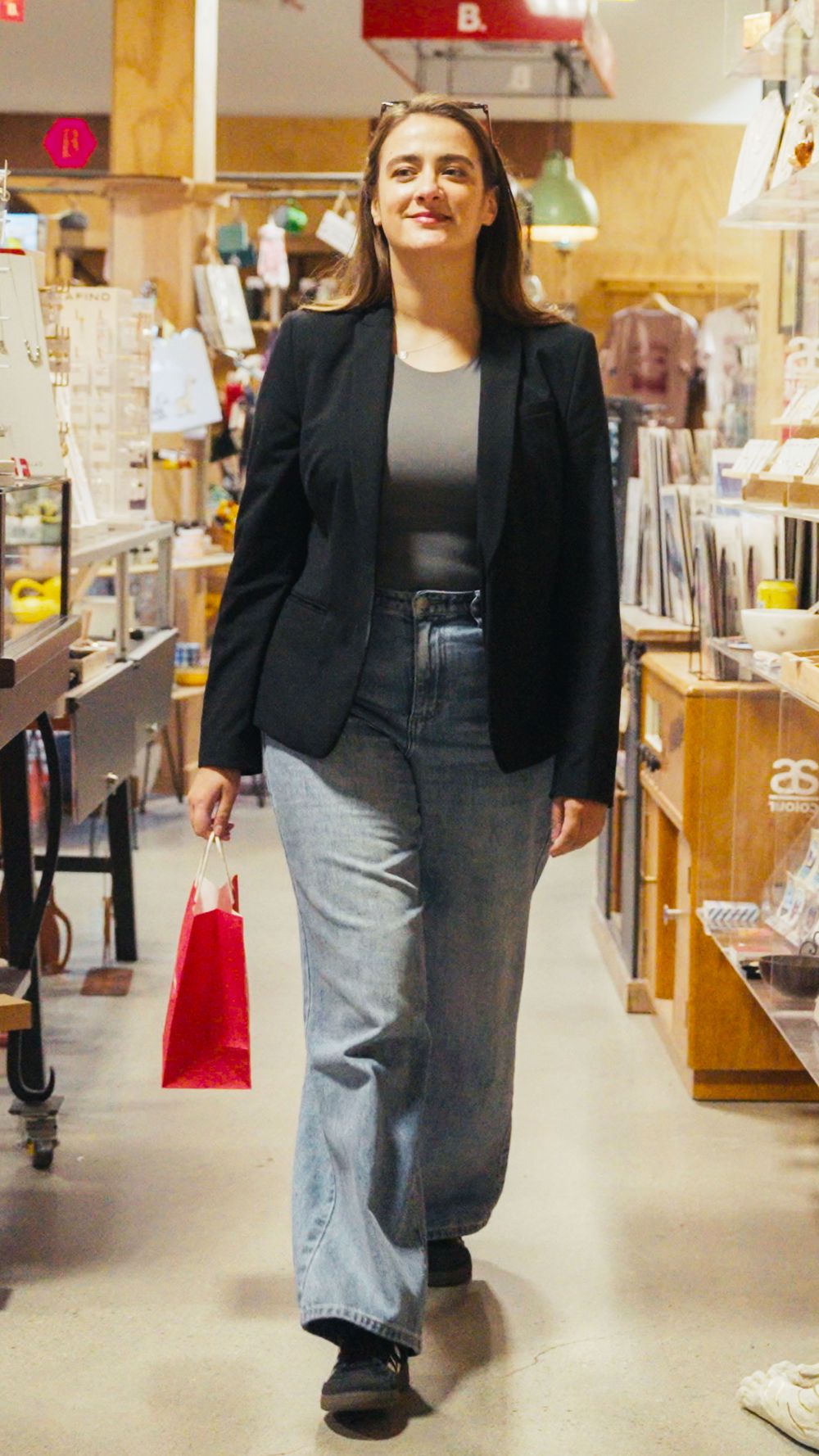 A shopper leaving a store with a red gift bag